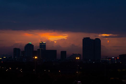 A city skyline silhouetted against a vibrant sunset, creating a dramatic urban scene.
