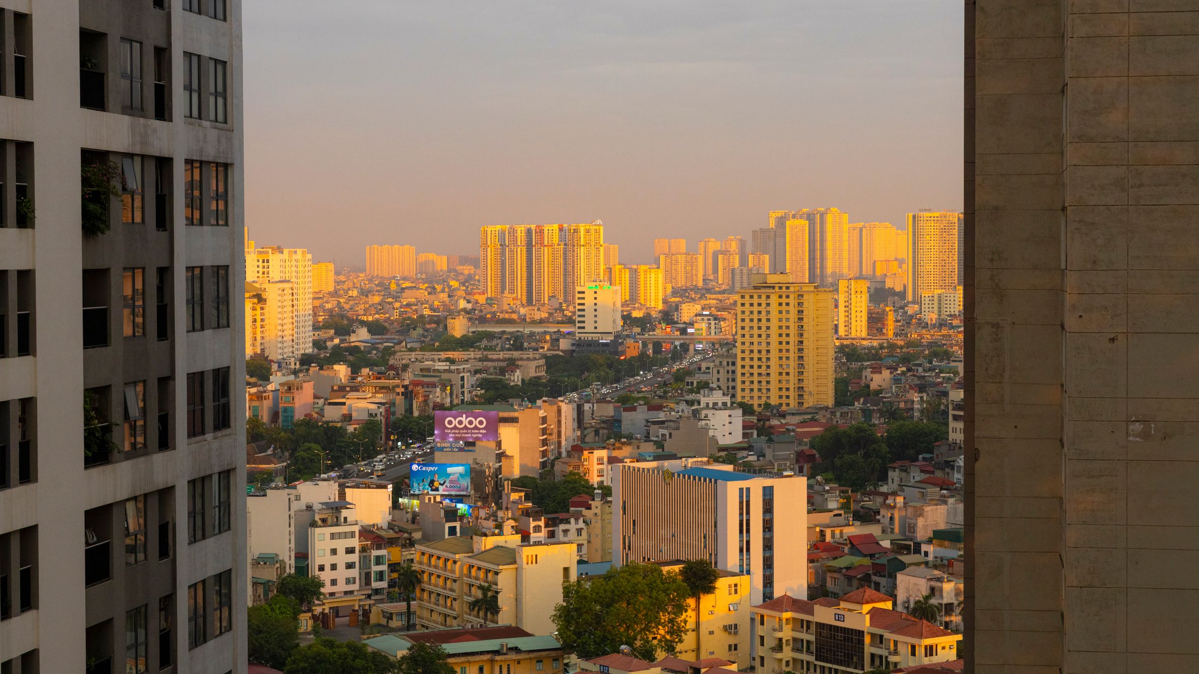 Stunning sunset over Hanoi cityscape with golden light reflecting on buildings, creating a warm urban atmosphere.