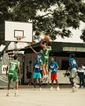 Vibrant outdoor basketball game with young adults playing passionately under a sunny sky.