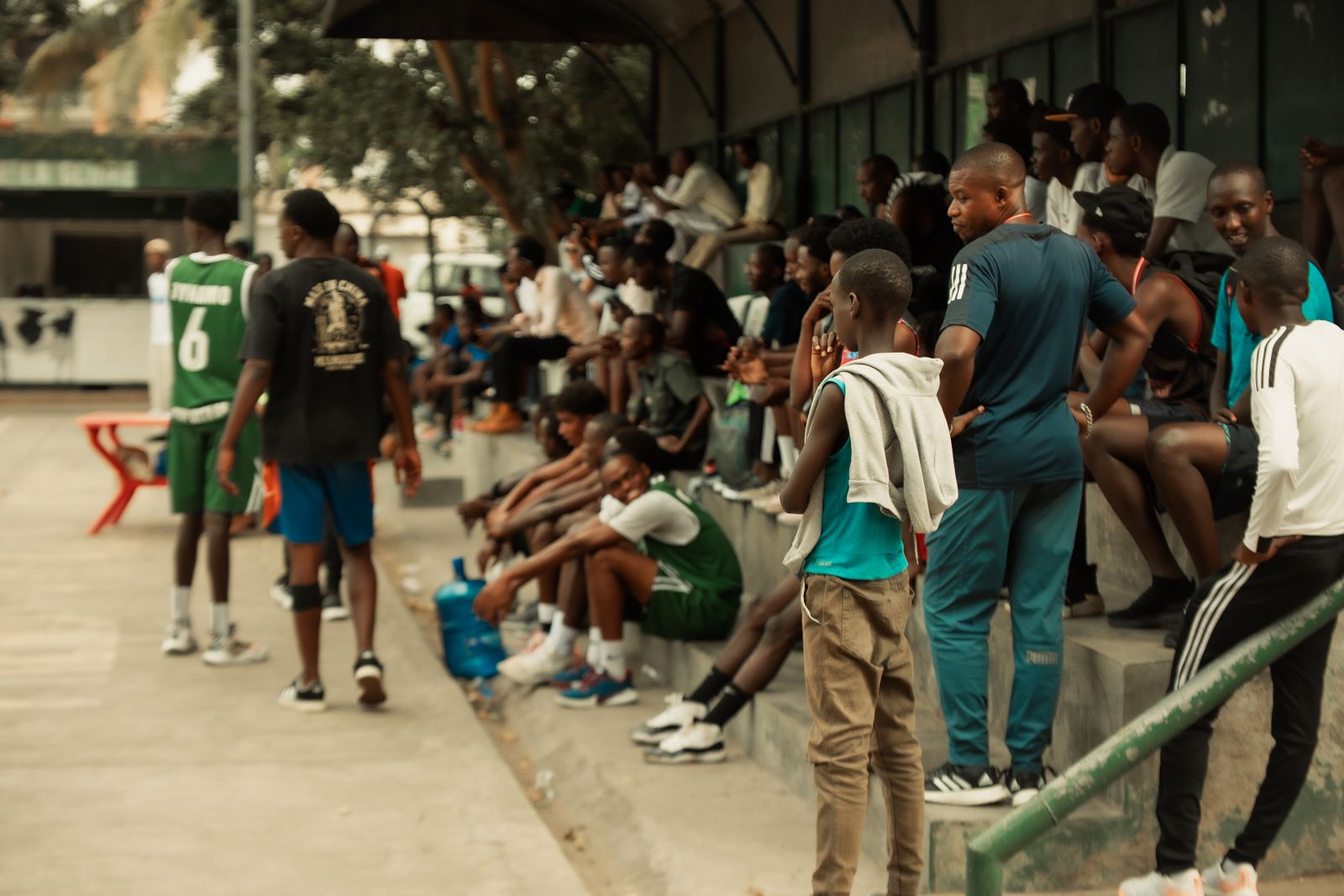 Público reunido à beira da quadra acompanhando uma partida de basquete ao ar livre