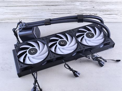 A modern triple fan CPU cooler with cables laid out on a concrete surface for cooling components.