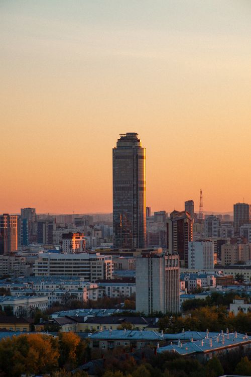 Free A striking view of a modern city skyline with a tall skyscraper at sunset. Stock Photo