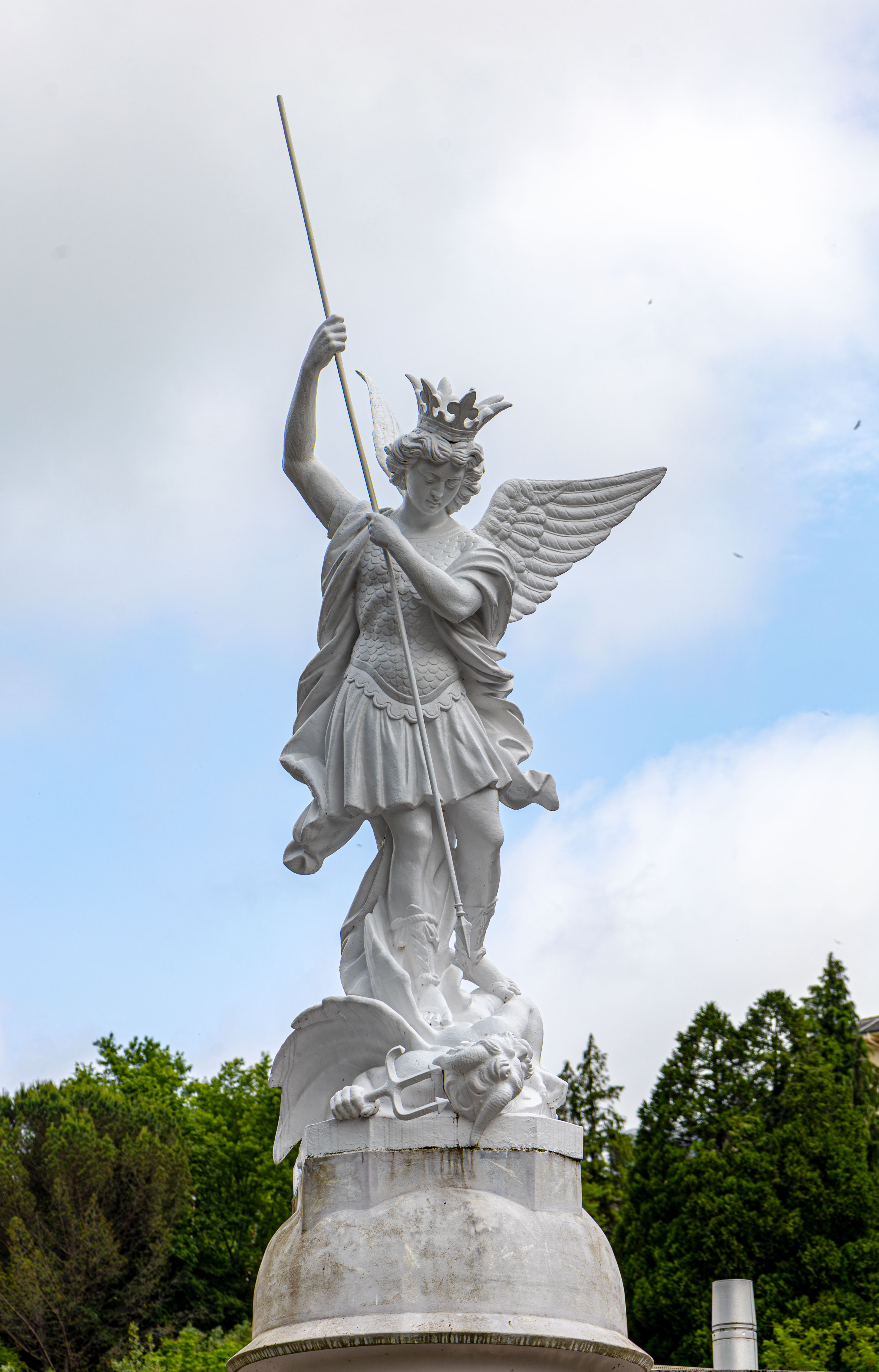 Majestic statue of Archangel Michael in the serene setting of Lourdes, France.