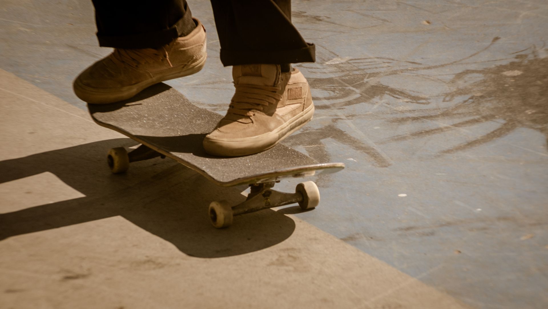 Close-up of a skateboarder's feet performing a trick at a skate park, capturing motion and balance.