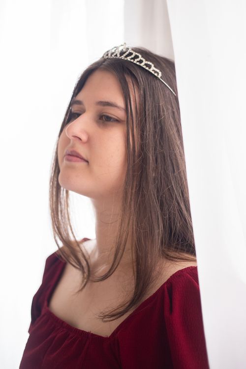 Free Elegant portrait of a young woman with a tiara against a soft white background, creating a serene and graceful mood. Stock Photo