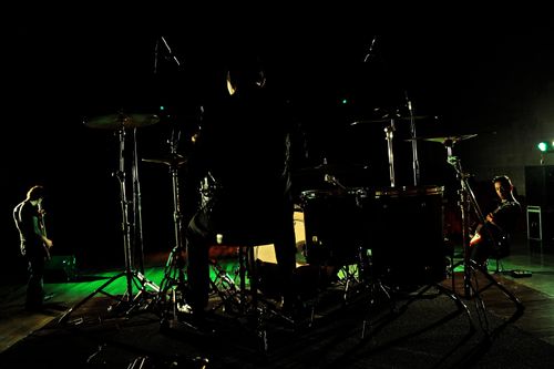 Free Dynamic stage performance by a rock band with drummer and guitarists under vibrant lights. Stock Photo