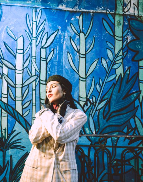Free Fashionable woman in a coat posing against colorful blue street art mural. Stock Photo