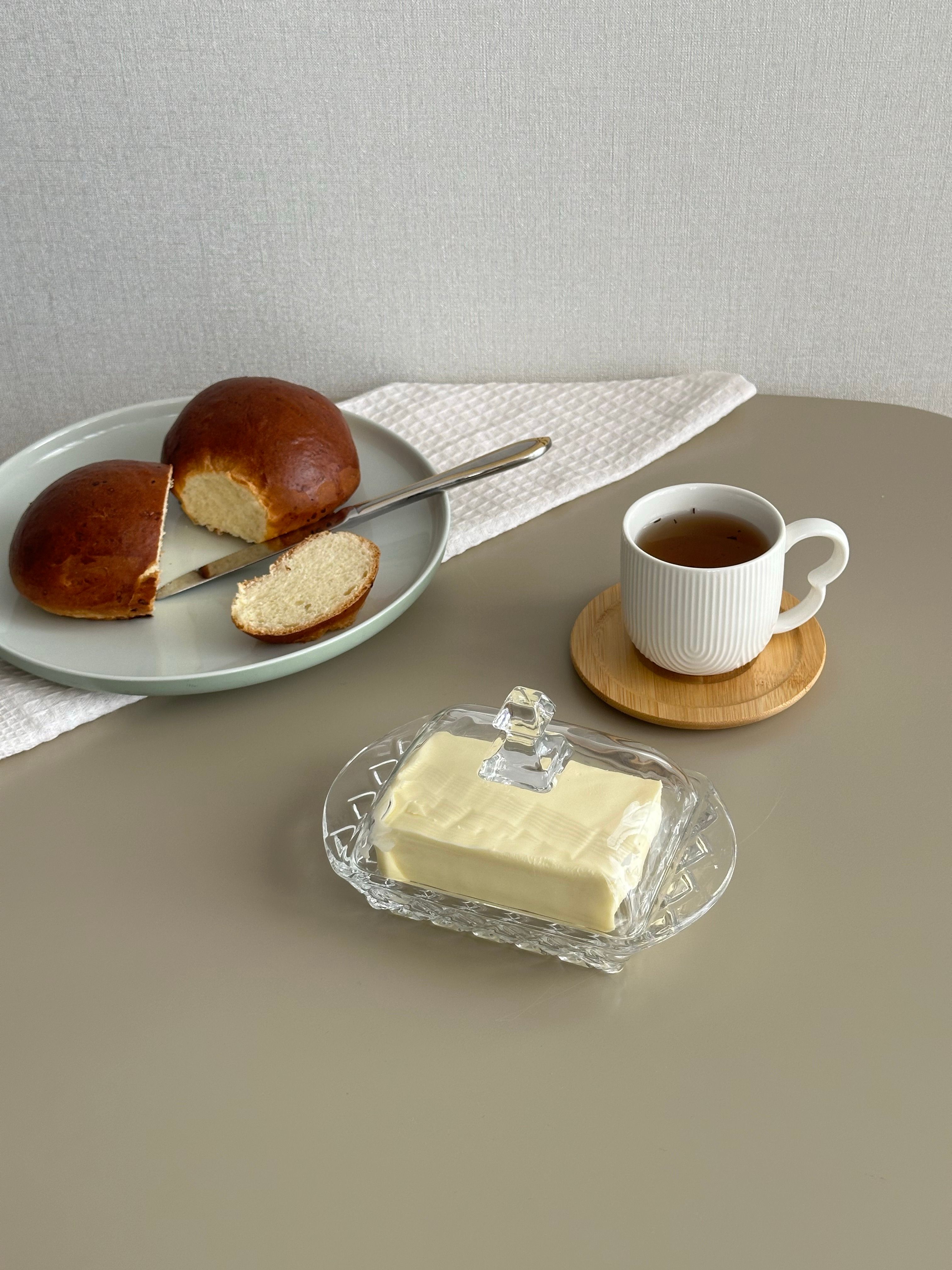 Minimalist breakfast setup with bread, butter, and tea on a sleek table.