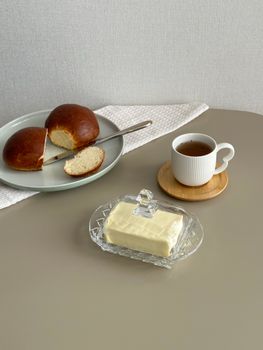 Minimalist breakfast setup with bread, butter, and tea on a sleek table.