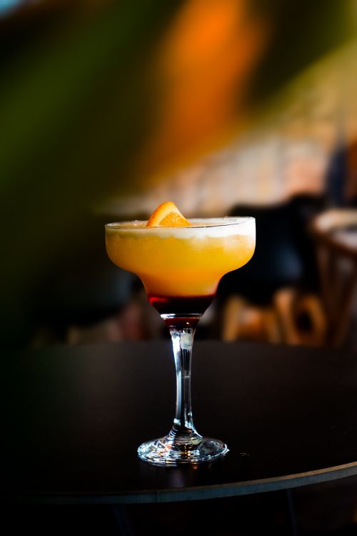 Free A refreshing citrus cocktail in a stylish glass set against a blurred bar ambiance. Stock Photo