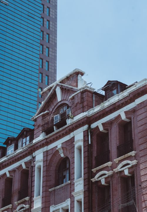 Free A classic red brick building stands in contrast to a modern skyscraper, blending past architectural styles. Stock Photo