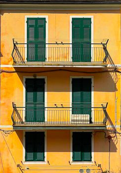 Bright yellow facade with green shutters in Venice, Italy, showcasing classic architecture.