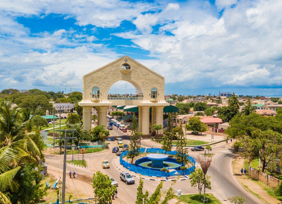 Scenic aerial view of Arch 22 in Banjul, The Gambia amid lush greenery and cloudy sky.