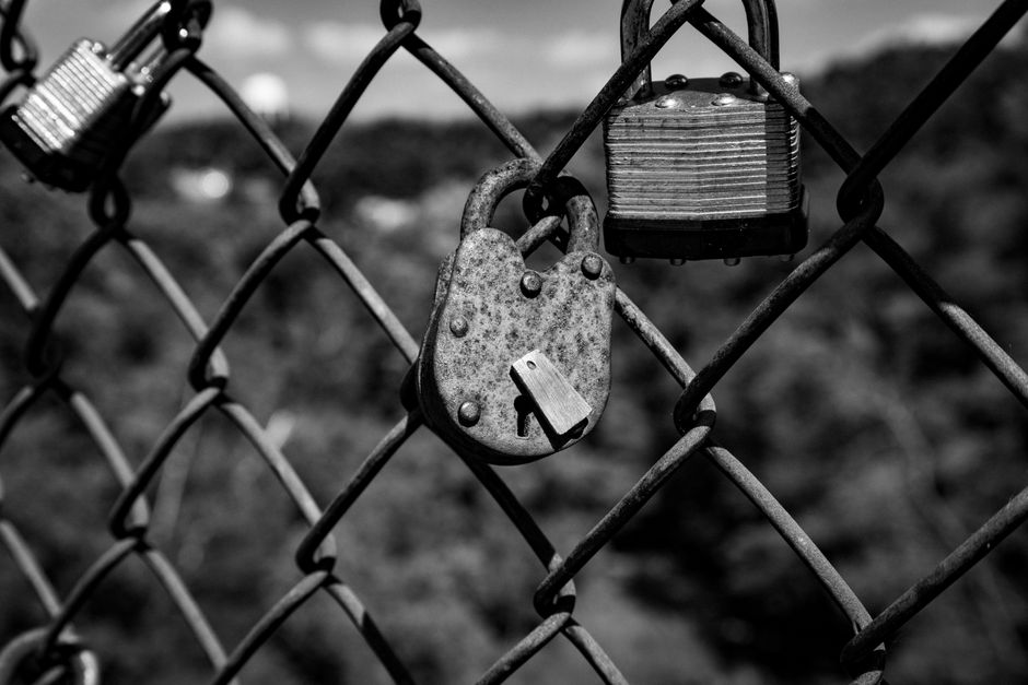 Black and white close-up of rusty padlocks on a fence symbolizing security and love.