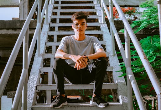 一名年轻人穿着休闲装，自信地坐在户外楼梯上