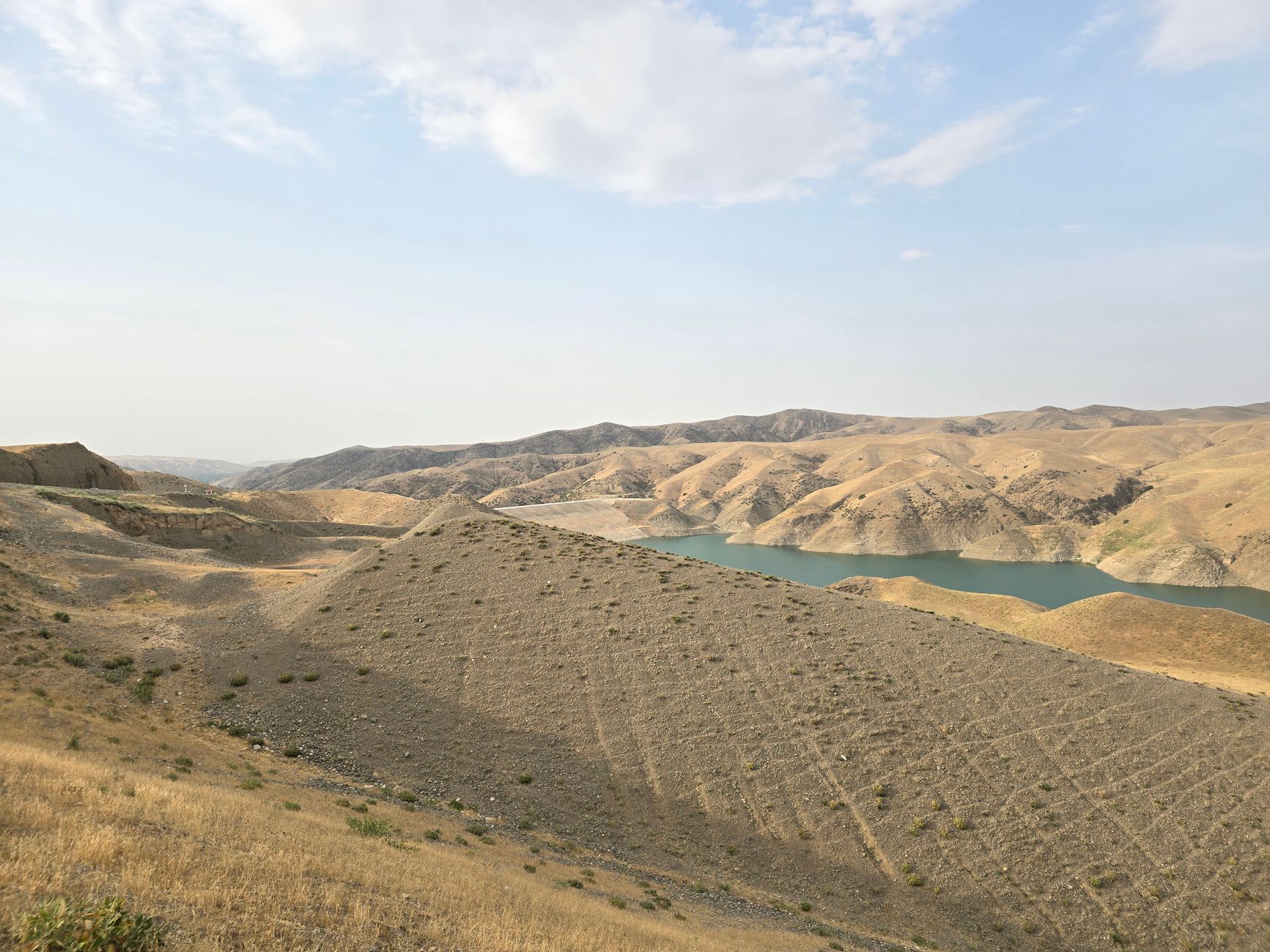 A picturesque view of an arid landscape with a blue reservoir and rolling hills in Uzbekistan.