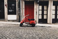 一辆迷人的红色黄蜂摩托车停在历史建筑前的鹅卵石街道上