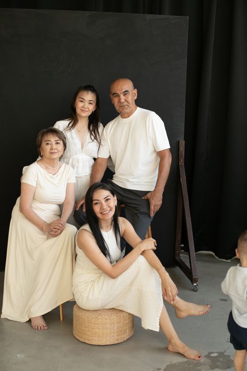 Free Smiling multigenerational family portrait indoors with four adults in white attire. Stock Photo