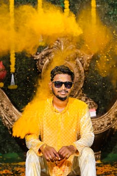 Joyful Indian man in traditional attire at a vibrant Haldi ceremony, covered in saffron powder.