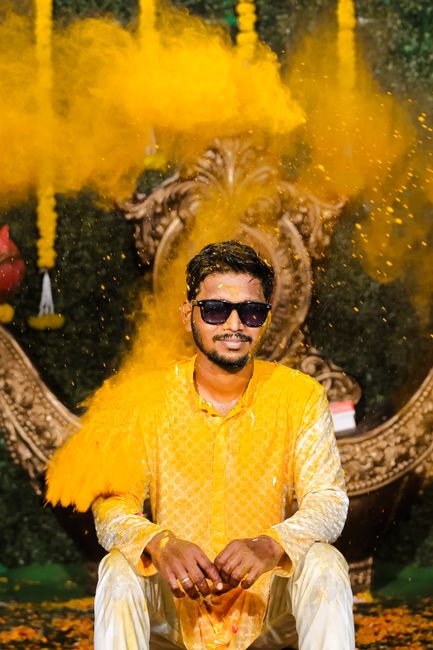 Joyful Indian man in traditional attire at a vibrant Haldi ceremony, covered in saffron powder.