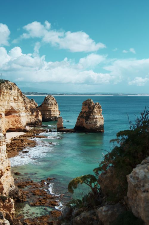 Free Breathtaking view of rock formations along the ocean in Lagos, Portugal, under a clear, bright sky. Stock Photo