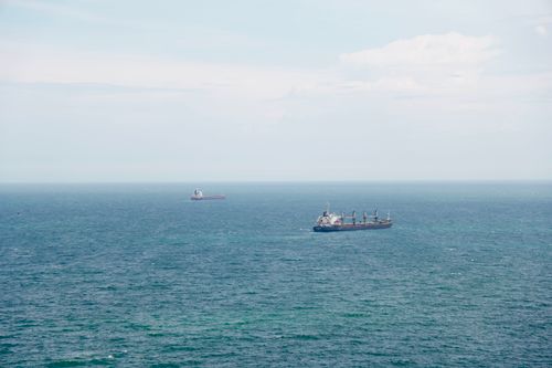 Free Two cargo ships navigating the expansive ocean under clear blue skies. Stock Photo