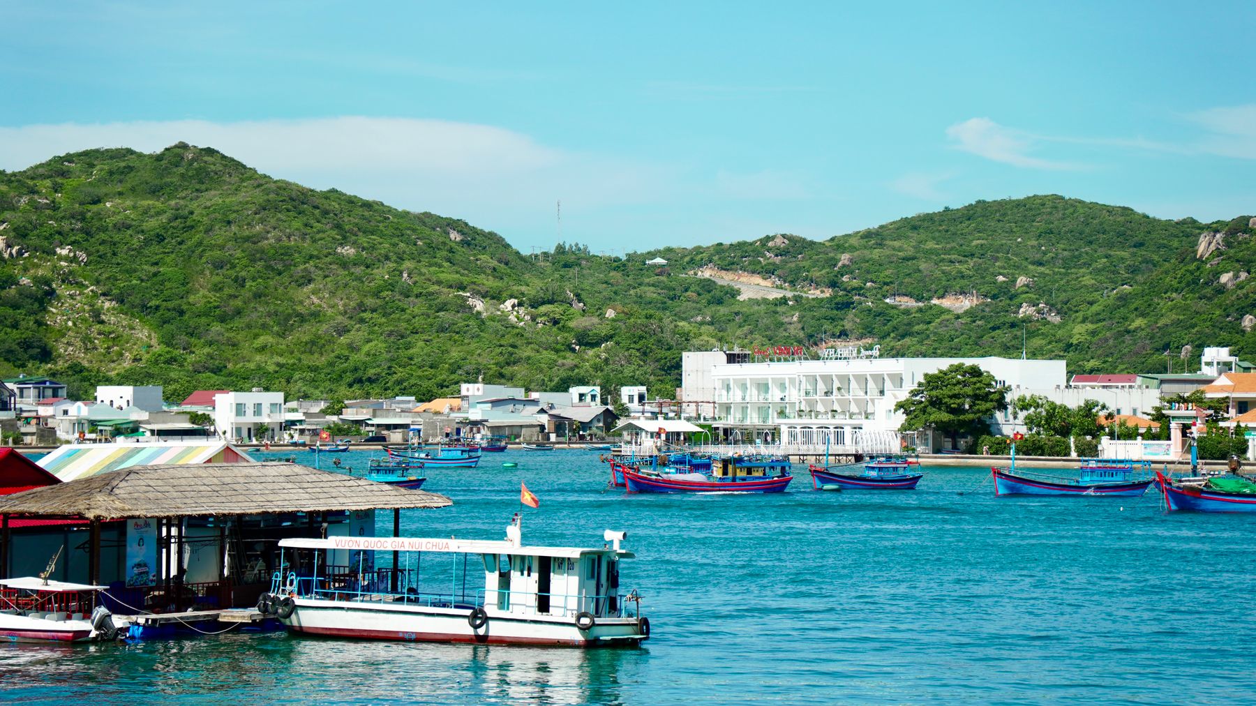 Làng chài ven biển đẹp như tranh vẽ với những con thuyền đầy màu sắc và những ngọn đồi xanh mướt dưới bầu trời trong xanh.