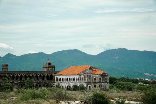 Abandoned historic building with mountain backdrop, showcasing architecture and natural scenery.