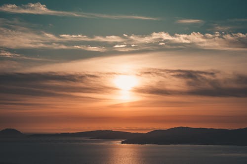 бесплатная Силуэтная фотография горы под пасмурным небом в золотой час Стоковое фото