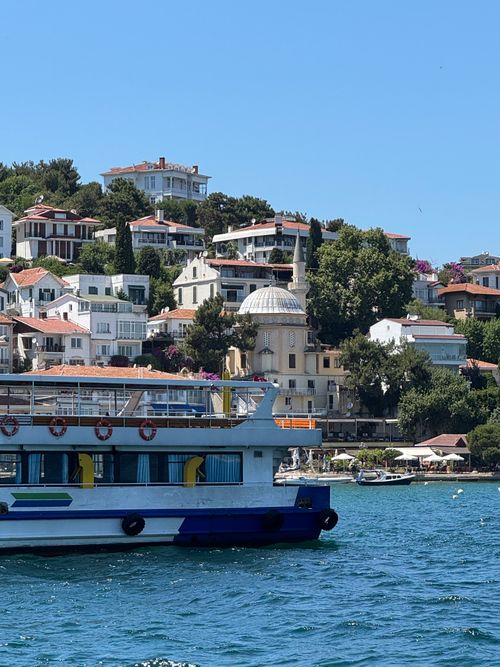 Free Colorful boat cruising near Istanbul's historic Bosphorus shoreline on a sunny summer day. Stock Photo