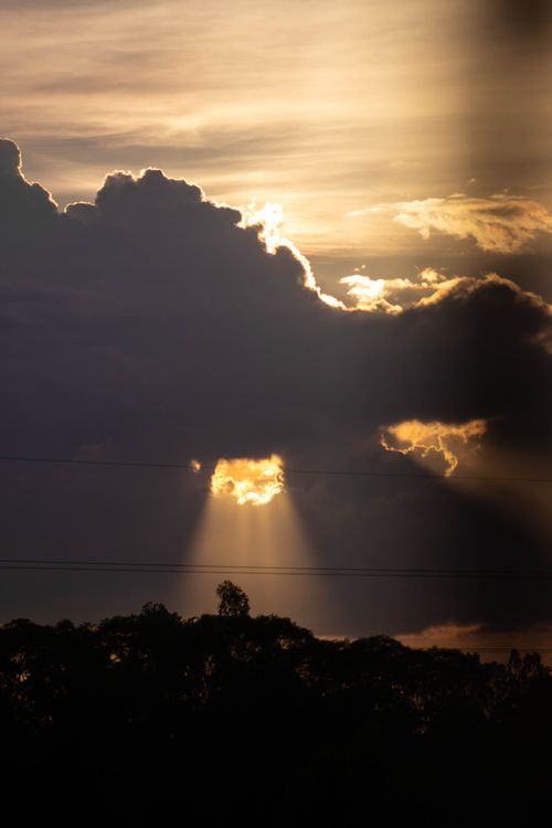 Free A captivating scene of sun rays piercing through dramatic clouds during sunset, creating a moody atmosphere. Stock Photo