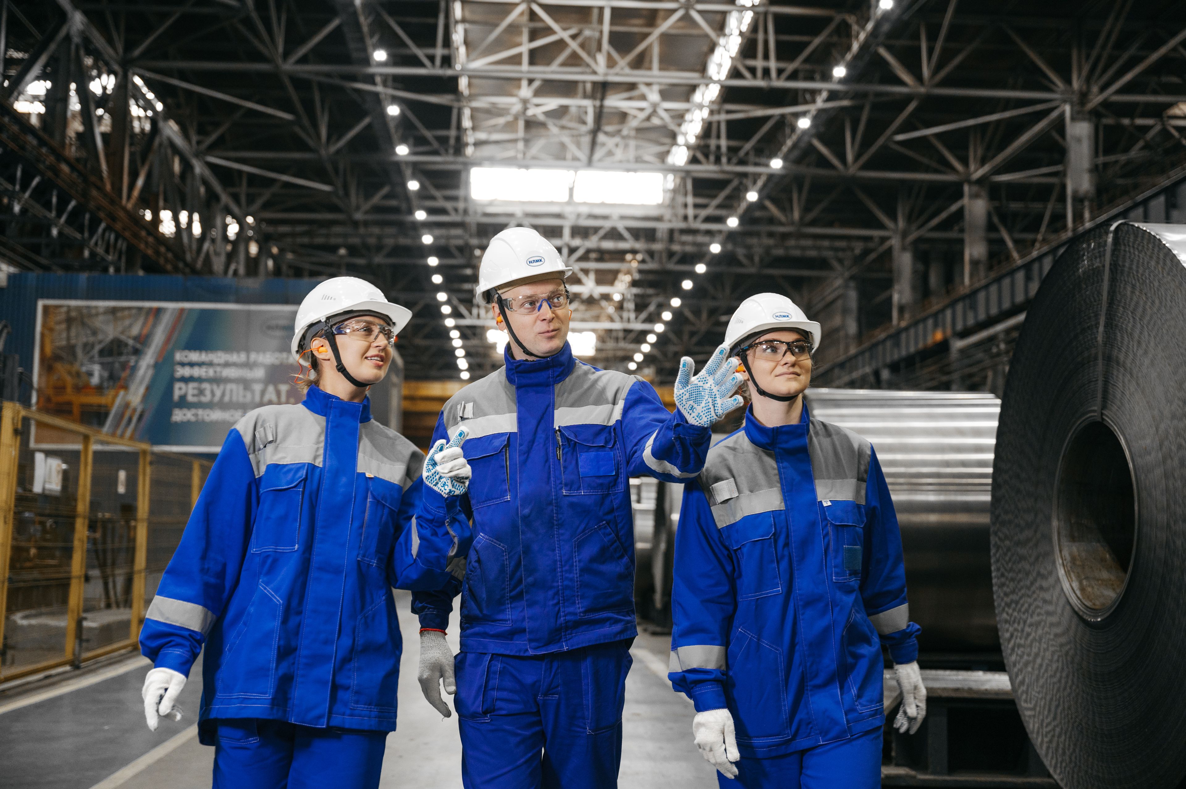 Workers in safety gear talking inside a steel factory