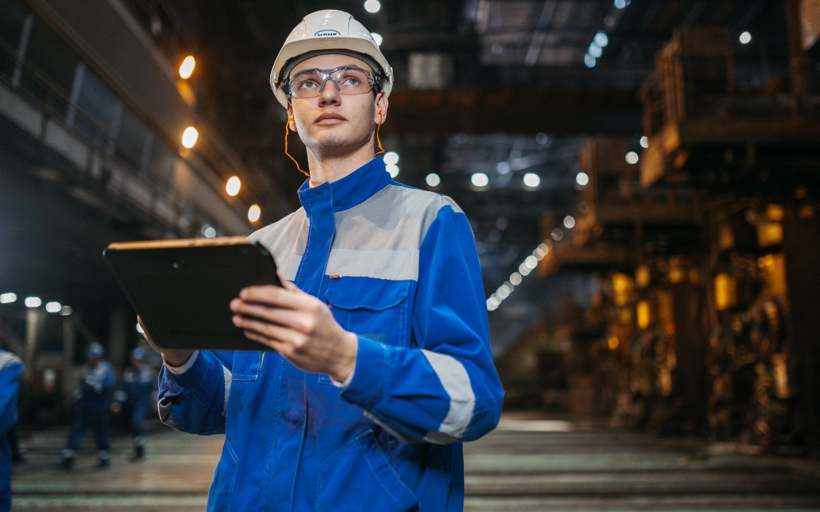 Ingeniero con equipo de protección consultando una tablet en planta