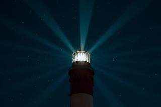 Lighthouse beam cutting through a starry night — photo by Maximilian Orlowsky on Pexels