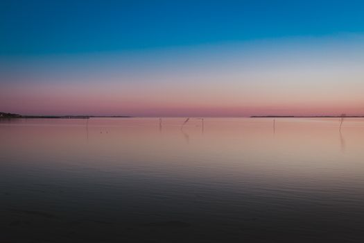 Tranquil twilight sea scene with vibrant gradient sky and calm waters.