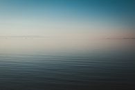 Tranquil seascape view at dawn with calm waters and a clear horizon.