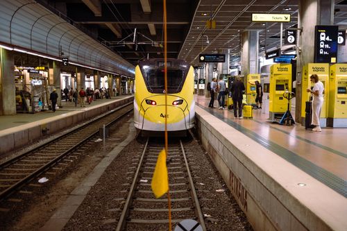 Free Yellow Arlanda Express train at Stockholm Central, platform bustling with travelers. Stock Photo