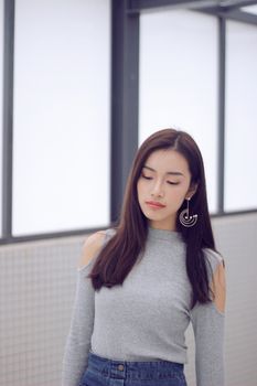 一位年轻亚洲女性身处时尚室内环境，佩戴着别致耳环，散发着优雅气质