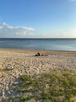 A serene beach scene with a person relaxing on the sand under the bright sun.