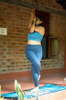 Woman in blue activewear performing yoga pose indoors on a blue mat.