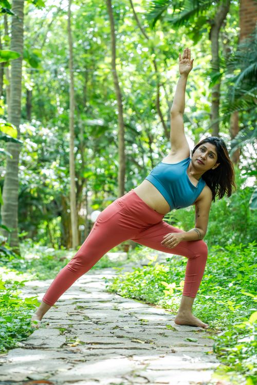 Free A woman performs a yoga pose on a stone path surrounded by vibrant greenery. Stock Photo