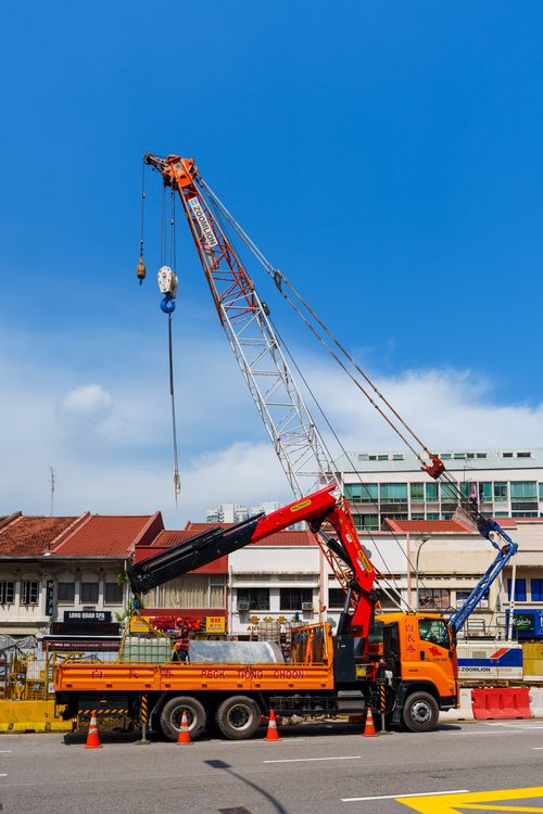 Free A vibrant construction scene with a crane and truck against a clear blue sky in an urban setting. Stock Photo