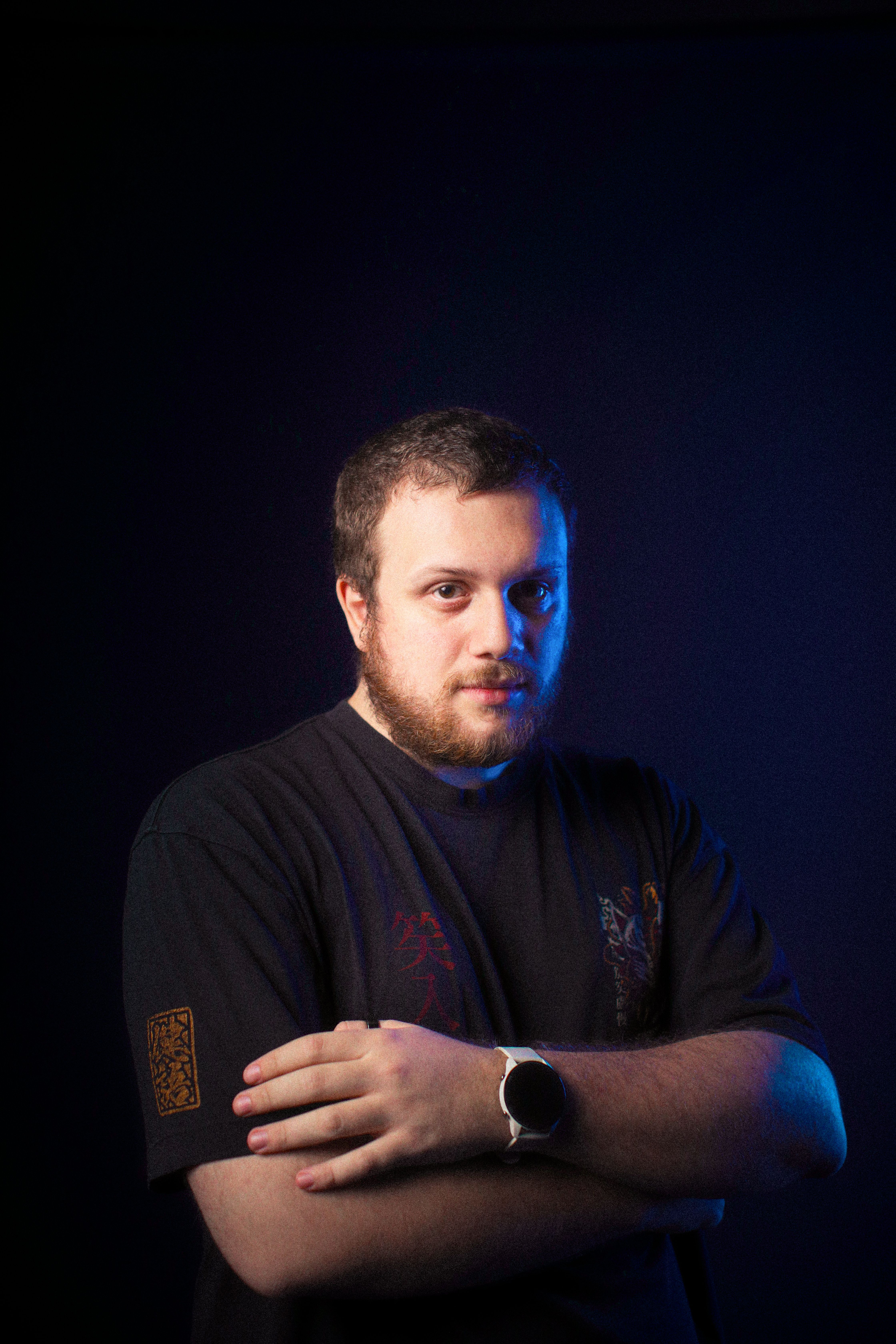 Styled portrait of a bearded man under dramatic lighting with a dark background.