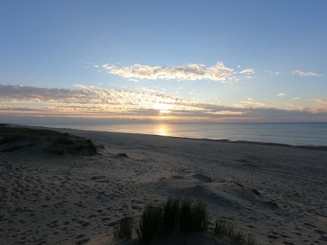 A peaceful sunset over the beach with soft waves and clear skies, perfect for relaxation.