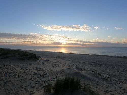 Free A peaceful sunset over the beach with soft waves and clear skies, perfect for relaxation. Stock Photo