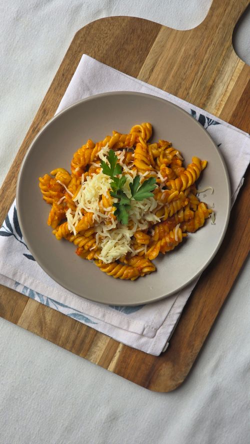 Free Rotini pasta topped with grated cheese and parsley on a wooden board, perfect for culinary inspiration. Stock Photo