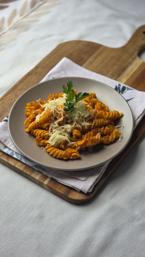 Free A plate of fusilli pasta in rich tomato sauce topped with cheese, served on rustic wooden board. Stock Photo