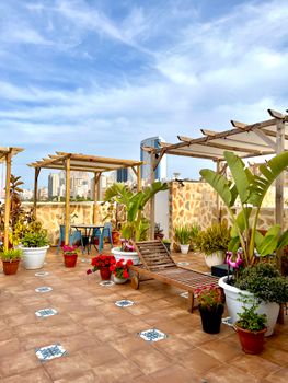 Beautiful rooftop garden with lounge chair, pergolas, and city skyline in view.