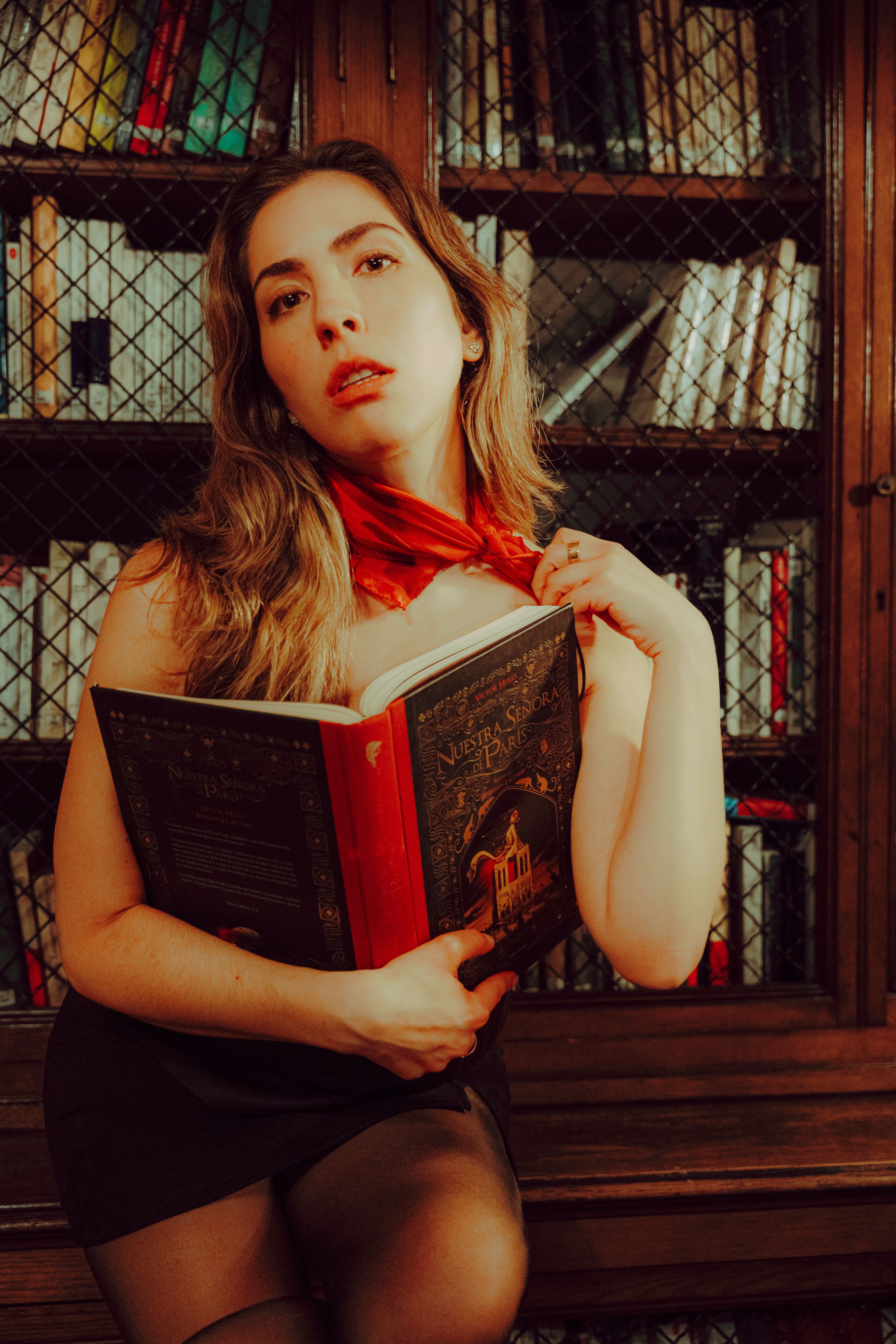 A young woman reading a book in a classic library, exuding a warm and vintage atmosphere.