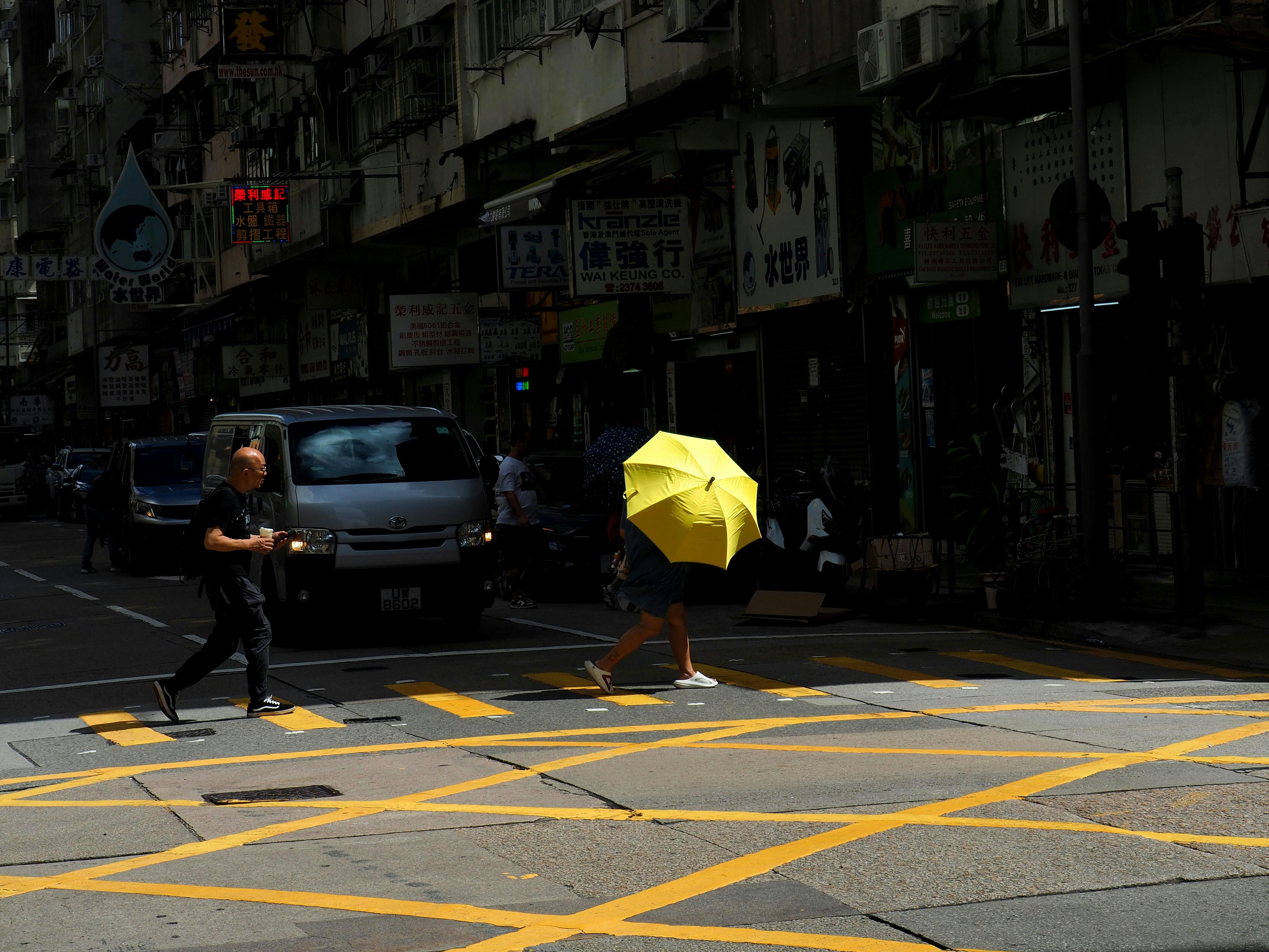 Colorful street scene in Hong Kong featuring people and a striking yellow umbrella.